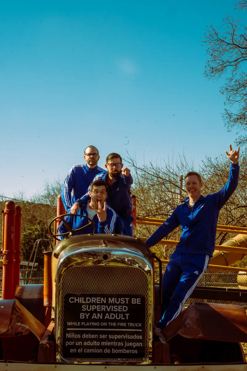 Band member throwing devil horns on a playground fire truck
